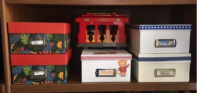 Bookshelf with toys, boxes, Daniel Tiger trolley